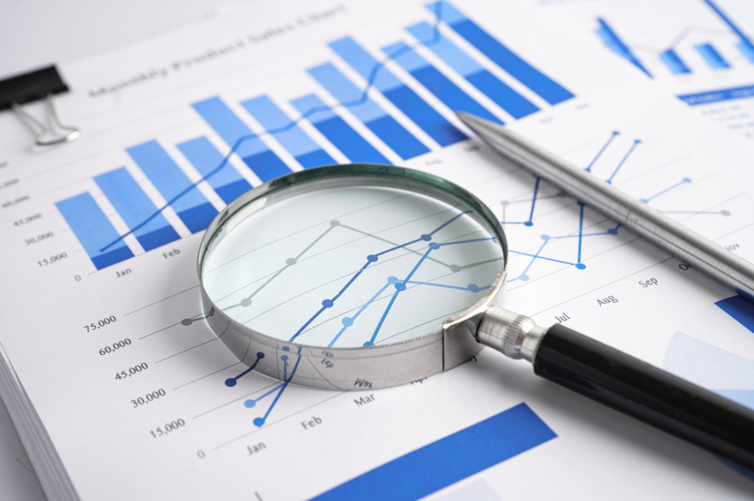 Accounting reports and charts under a magnifying glass.