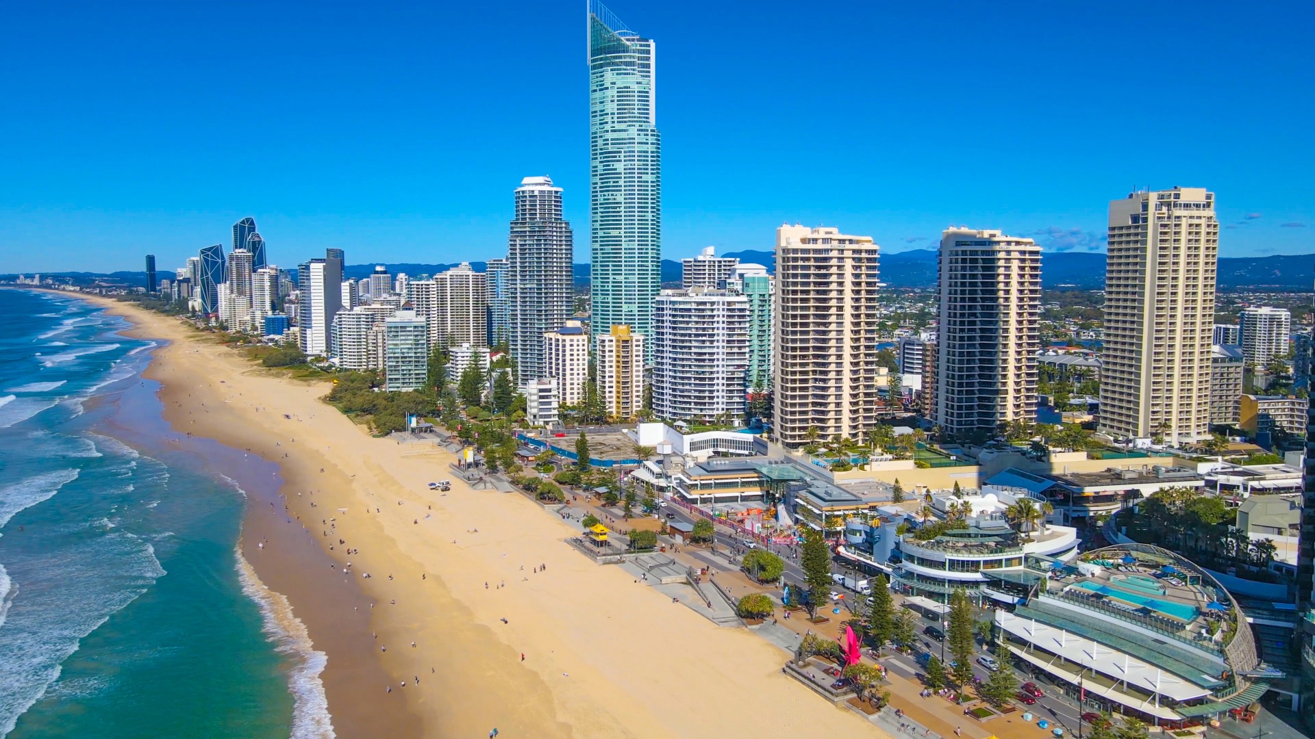 Aerial view of the Gold Coast beachfront and skyline on a bright blue day.